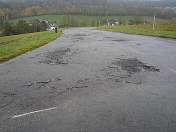 Eher einem Schweizer K&auml;se als einer Gemeindeverbindungsstra&szlig;e gleicht derzeit der Mirsdorfer Weg  in Neukirchen. Vor Wintereinbruch sollen die schadhaften Stellen geschlossen werden. Foto: Martin Rebhan