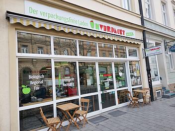 Der Bamberger Unverpacktladen schließt nach sieben Jahren. Vor dem Geschäft stehen Tische und Stühle. Schilder werben für Bioprodukte und Nachhaltigkeit.