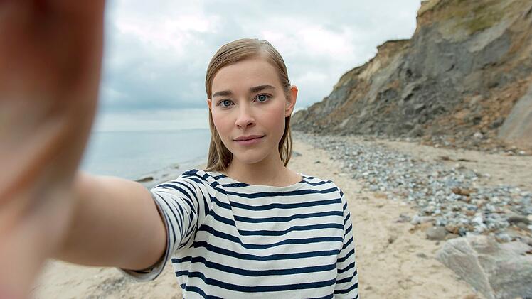 Umwelt-Influencerin Zenaida (Milena Tscharntke) macht ein Video am Strand.