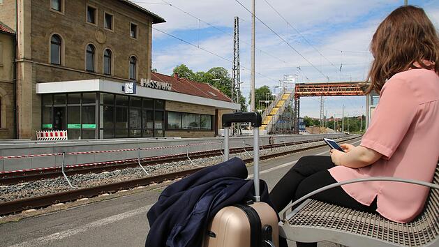Eine junge Frau wartet mit gepacktem Koffer am Bahnhof in Haßfurt. Wohin wohl die Reise geht? Mit der Bahn zum nächsten Flughafen und dann ins Ausland - oder per Zug zum inländischen Reiseziel ?  Foto: Jutta Rudel