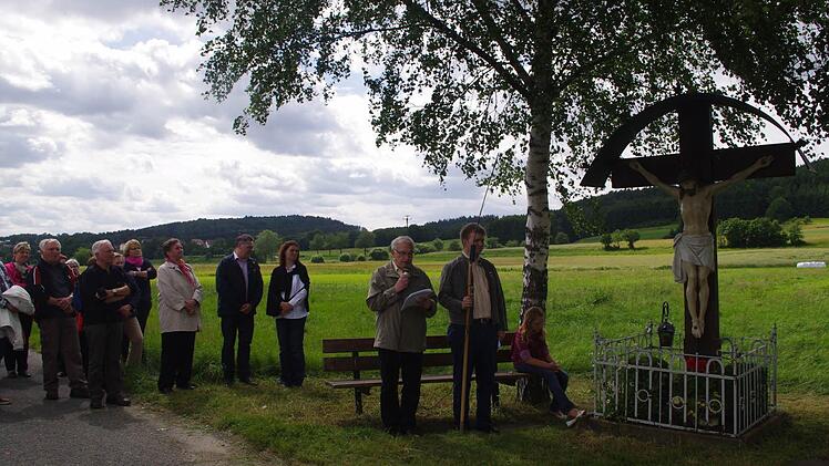 Der Vorsitzende des Pfarrgemeinderats, Rudolf Hanna (vorne links), und Pfarrgemeinderat Bernd Schnappauf (daneben) befinden sich hier beim Wegkreuz am Radweg nach Dörfles. Mit im Bild ist die zehnjährige Lena (sitzend) aus Friesen als jüngste Wallfahrerin.