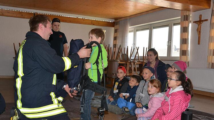 Joel kann sich selbst davon überzeugen, wie schwer eine Pressluftatmer ist, den der Feuerwehrmann beim Einsatz tragen muss.  Foto: Björn Hein