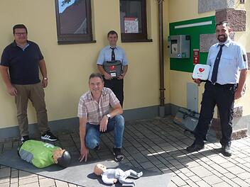 Peter Brunner (von links), Ortsbeauftragter Bernd Hüfner (kniend), Stellvertretender Kommandant Marko Koch und 1. Kommandant Dennis Frey bei der Vorstellung des neuen Defibrillators am Feuerwehrhaus.