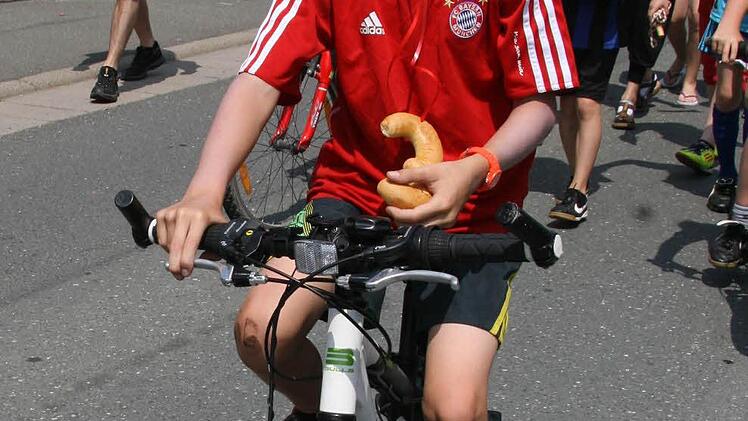 Doppelt gemoppelt hält besser: Der Bayern-Fan trägt nicht nur ein Fußballtrikot, sondern kommt auch noch mit einem Rad.