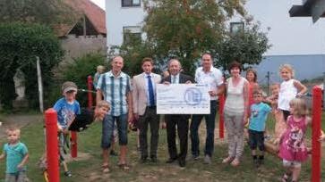 Vertreter der Allianz haben bei der Einweihung der Spielgeräte für die Kindertagesstätte Wasserlosen einen symbolischen Scheck überreicht. Auch andere regionale Firmen hatten das Projekt unterstützt.  Foto: Kita