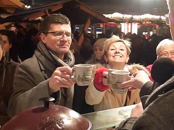 Ein Tässchen Glühwein zum Aufwärmen: Mäc Härder, Heidi Schütz und Jo Farmer bei ihrem Rundgang auf dem Bamberger Weihnachtsmarkt.