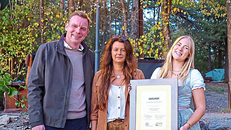 Gastronomin Sandra Kaiser nahm zusammen mit Mitarbeiterin Jenny Niebling (rechts) f&uuml;r ihre Weinbergsh&uuml;tte Vinica die Auszeichnung Lieblingsbiergarten 2026 aus den H&auml;nden von Martin Wende entgegen. Rudi Merkl