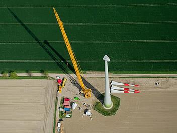 Ein neues Windrad wird mit Hilfe eines großen Krans montiert (Luftaufnahme). Foto: Julian Stratenschulte/dpa
