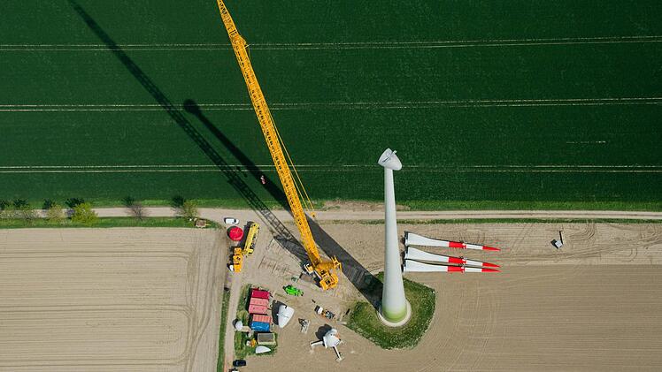 Ein neues Windrad wird mit Hilfe eines großen Krans montiert (Luftaufnahme). Foto: Julian Stratenschulte/dpa