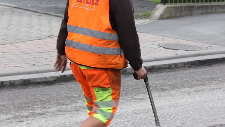 Carsten Novotny sprüht Farbe auf die Fahrbahn. Danach kann sich der Lenker der Asphaltierungsmaschine richten. Foto: Friedwald Schedel