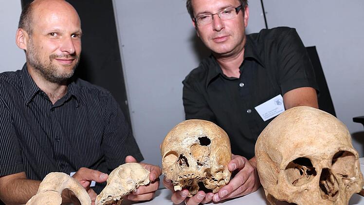 Professor Andreas Schäfer (links) und Projektleiter Timo Seregély präsentieren die Schädel eines Erwachsenen (rechts) und eines Jugendlichen sowie weitere menschliche und tierische Knochen. Foto: Matthias Hoch
