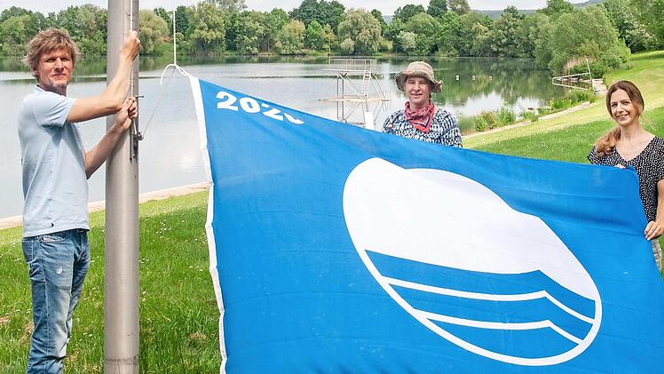 Martin L&uuml;ders (Freizeit-GmbH), Anne Schmitt (Flussparadies Franken) und Anne-Maria Schneider (Kur- und Tourismus-Service) beim Hissen der Blauen Flagge am Ostsee in Bad Staffelstein. Foto: Flussparadies Franken
