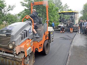 Im Wiesenweg in Pressig wird mit dem Asphaltfertiger der Asphalt aufgetragen. Andreas Schorn und Bürgermeister Stefan Heinlein sprechen mit Christian Heiß (Geschäftsführer der Firma GSG, von links).  Foto: Karl-Heinz Hofmann