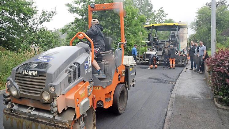 Im Wiesenweg in Pressig wird mit dem Asphaltfertiger der Asphalt aufgetragen. Andreas Schorn und Bürgermeister Stefan Heinlein sprechen mit Christian Heiß (Geschäftsführer der Firma GSG, von links).  Foto: Karl-Heinz Hofmann