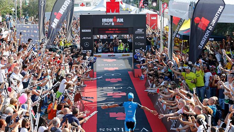 Erst lässt Andreas Dreitz (Mitte) alle Konkurrenten hinter sich, dann genießt  er das Bad in der Menge: Der Zieleinlauf des Michelauers beim Ironman    Emilia Romagna  ist ein  Triumphzug.  dpa