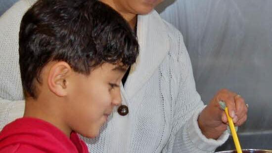 Der kleine Achmed (7) aus Syrien beim Kochen mit der Albanierin Figirete. Foto: Sigismund von Dobschütz