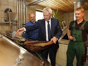 Die Braumeister Josef Lindner und (links) und Hannes Grasser (rechts) vetrauen Landrat Johann Kalb die Hopfengabe an. Fotos: Matthias Hoch