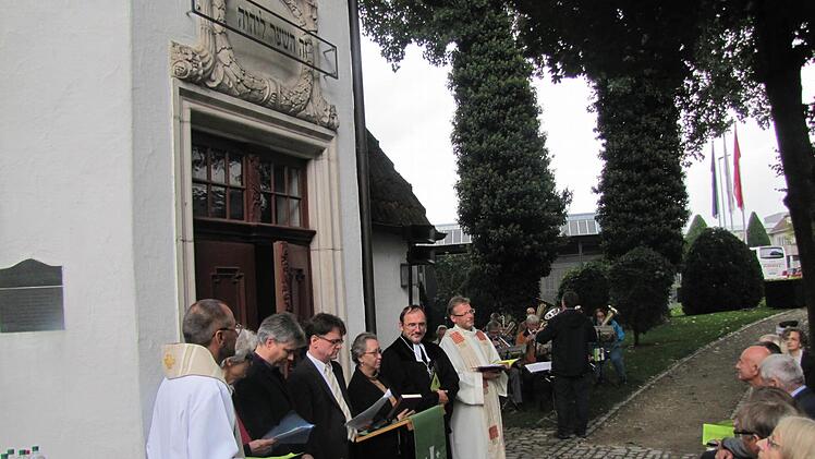 Vor der Nikolauskapelle und unter der hebräischen Inschrift feiern Gottesdienst (von links): der römisch-katholische Dekan Roland Huth, Christl Grünberg und Wolfgang Graf von der alt-katholischen Kirchengemeinde St. Nikolaus, Pastor Sebastian Thierfelder von den Baptisten, Rabbinerin Dr. Antje Yael Deusel, der evangelisch-lutherische Dekan Andreas Kleefeld und der alt-katholische Pfarrer Hans-Jürgen Pöschl. Foto: Martin Koch