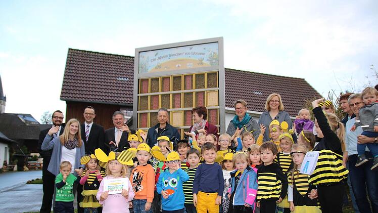 Die Kindergarten-Kinder und die Offiziellen vor der Wildbienen-Wand.