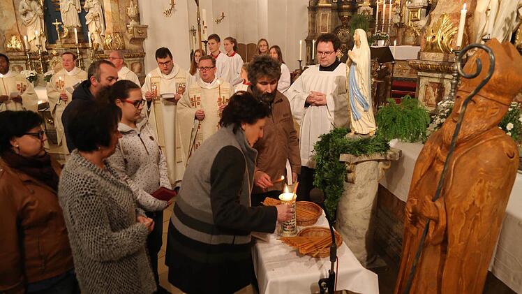 Gottesdienstbesucher zünden ihre Kerzen bei der Madonna zur Prozession an. Foto: Franz Galster