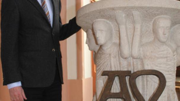 Dekan Hans Roppelt weist auf das Alpha- und Omega-Symbol am modernen Ambo hin.  Foto: Sonny Adam