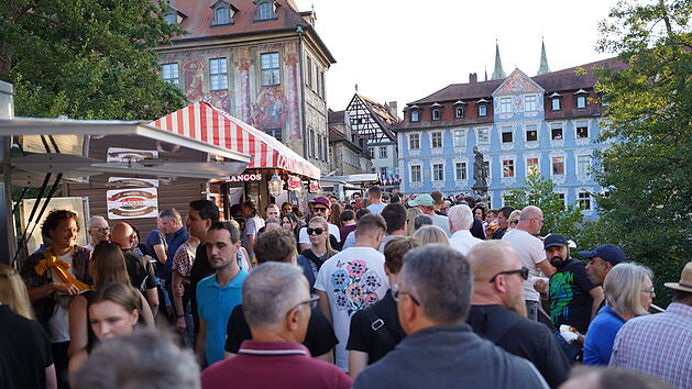 Menschenmenge auf der Bamberger Sandkerwa 2025, umgeben von historischen Geb&auml;uden. Verk&auml;uferst&auml;nde s&auml;umen die Stra&szlig;e, Besucher genie&szlig;en die festliche Atmosph&auml;re.