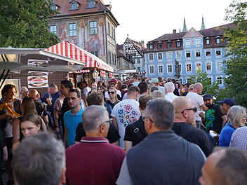 Menschenmenge auf der Bamberger Sandkerwa 2025, umgeben von historischen Gebäuden. Verkäuferstände säumen die Straße, Besucher genießen die festliche Atmosphäre.