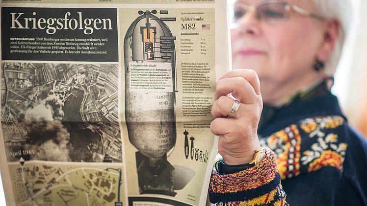 Eine Dame liest am 17.03.2013 in der Evakuierungs-Sammelstelle im Eichendorff-Gymnasium in Bamberg eine Ausgabe des Fränkischen Tags, die auf Sonderseiten über die Evakuierung und Kriegsfolgen im Allgemeinen informiert.