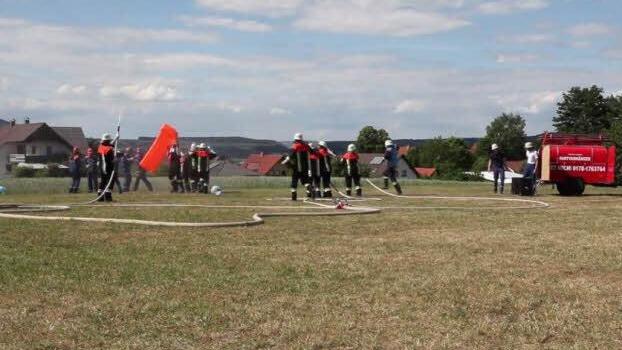 Bei ihrer "Cold Water Challenge" hat die Wolfsdorfer Feuerwehr mit einer Drohne gefilmt. In dem Video spielen die Feuerwehrler die Suche nach einem "Paar" nach, das sie auf einer Wiese entdecken. Es wird nass gemacht. Danach wird getanzt und herumgehüpft. Video: Feuerwehr Wolfsdorf