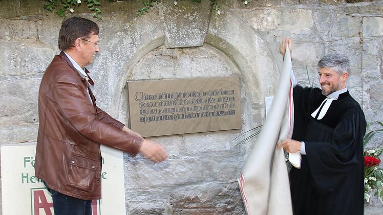Der Vorsitzende des Fördervereins für Heimatpflege in Grub am Forst gab zusammen mit Pfarrer Thomas Amberg die Tafel an der Kirchenmauer der St.-Ägidius-Kirche frei. Foto: Michael Stelzner