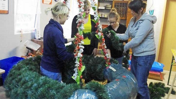 Simone Porzig, Carina Jakob, Laura Beetz und Nicole Gerber (von links) binden kunstvoll den Maibaum-Kranz. Dabei ist viel Geschick gefragt. Foto: Heike Schülein