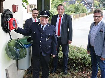 Nicht ganz ohne Stolz hängt der Kommandant der Weißenbrunner Wehr, Friedrich Knabe, das Gerät in den Wandkasten. Die Unterstützer, Stefan Schneyer und Marco Seiler, sowie Bürgermeister Rolf Rosenbauer freuen sich über ein Stück mehr Sicherheit in Weißenbrunn am Forst.