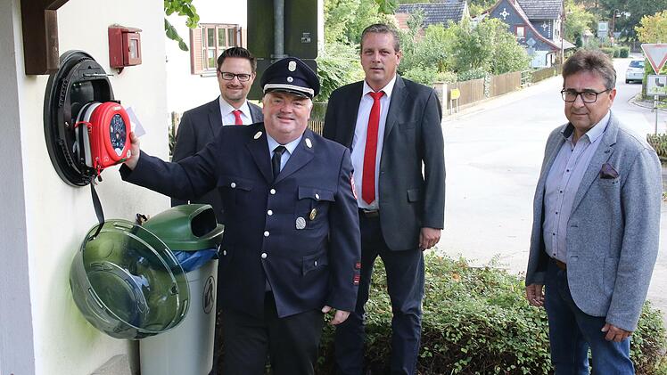 Nicht ganz ohne Stolz hängt der Kommandant der Weißenbrunner Wehr, Friedrich Knabe, das Gerät in den Wandkasten. Die Unterstützer, Stefan Schneyer und Marco Seiler, sowie Bürgermeister Rolf Rosenbauer freuen sich über ein Stück mehr Sicherheit in Weißenbrunn am Forst.