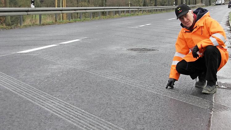 Jürgen Woll zeigt auf die Fräsrillen im Asphalt der Bundesstraße 303 bei Weißenbrunn.  Foto: Friedwald Schedel