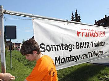 Steffen Kölbl, Jonas Bunzelt und Michael Schardt (v.l.) bringen einige Wochen vor dem Termin die Banner für die Radtourpur an.  Foto: Stefan Lutter