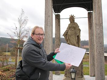 Stadtpfarrer Thomas Eschenbacher zeigt einen Plan der Schale mit Spatz darauf, die er vor der schwangeren Madonna an der neuen Saale-Brücke aufstellen lassen will. Foto: Ralf Ruppert