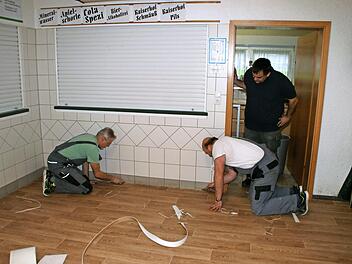 2. Vorsitzender Holger Bogdanski (stehend) beobachtet die letzten Arbeiten von Rainer Daum und Norbert Fleischmann (v. l.) beim Verlegen des neuen Fußbodenbelages in der Zecherhalle.  Foto: Joachim Beez