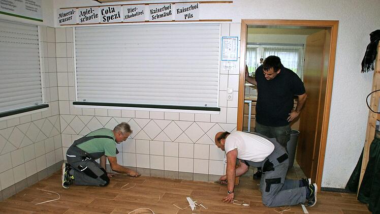 2. Vorsitzender Holger Bogdanski (stehend) beobachtet die letzten Arbeiten von Rainer Daum und Norbert Fleischmann (v. l.) beim Verlegen des neuen Fußbodenbelages in der Zecherhalle.  Foto: Joachim Beez