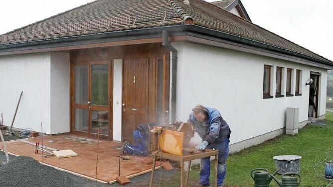 Uwe Gareis von der Firma Helmut Herrmann schneidet die Pflastersteine zu, sein Kollege Stefan Tasler verlegt sie vor der Leichenhalle. Foto: Sonja Adam