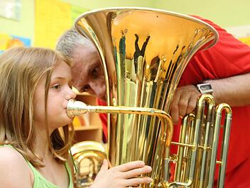 Lena (7) probiert eine Tuba aus, Thomas Bogner von den Eschenbacher Musikanten hilft ihr. Foto: Markus Reeh