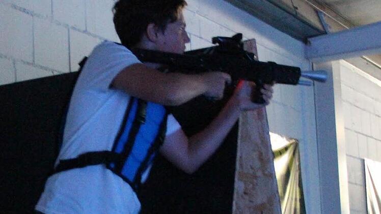 Simon trägt als Ausrüstung Weste und Gewehr.