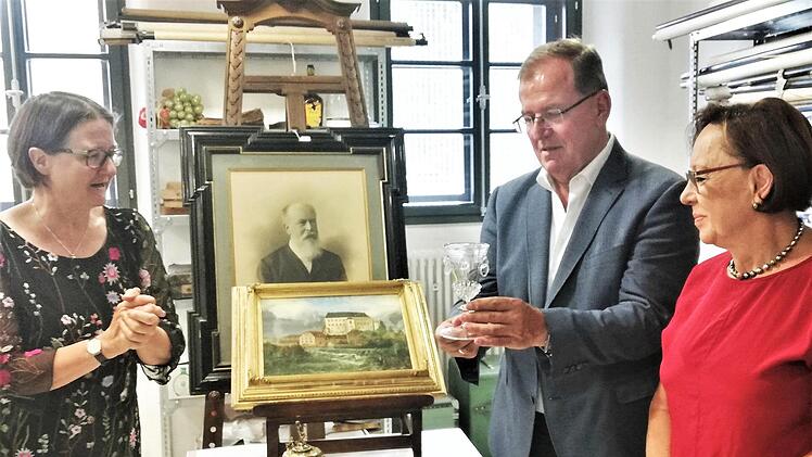 Bezirkstagspräsident Erwin Dotzel (CSU) und Bezirksrätin Karin Renner (CSU; rechts) lassen sich im Museumsdepot von Birgit Speckle (links) einige Exponate der künftigen Ausstellung zeigen.