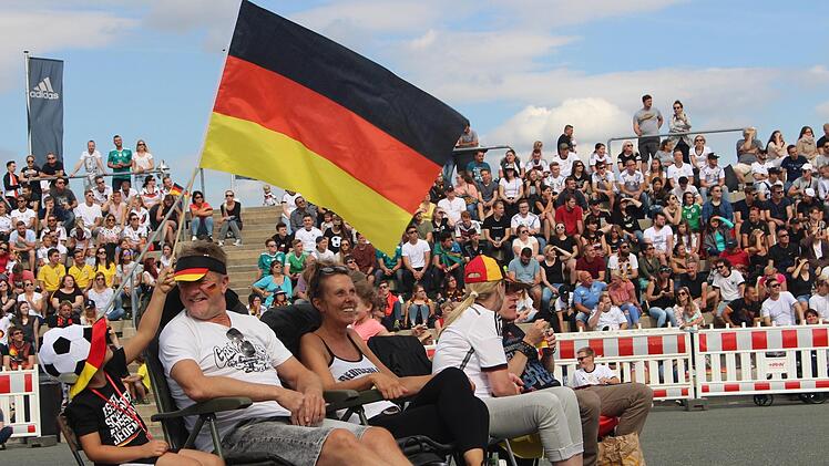 Der kleine Marcel schwenkt auf der Adidas-Piazza die Fahne und auch Georg und Silke sind wenigstens bis zur 35. Minute noch guter Dinge.  Fotos: Yannick Hupfer, Bernhard Panzer