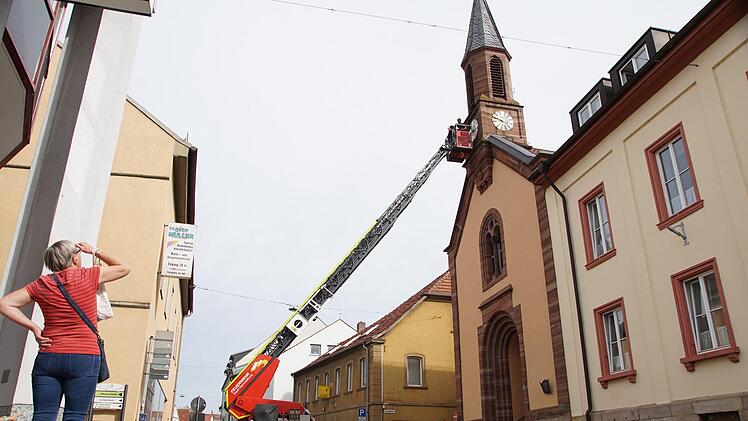Eine Passantin beobachtet, was an der Uhr der Bürgerspitalkirche vor sich geht.  Foto: Arkadius Guzy