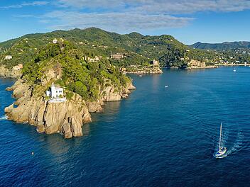 Luftaufnahme des historischen Leuchtturms Faro di Portofino im Ferienort Portofino, Ligurien, Italien. Der ikonische Leuchtturm thront auf dramatischen Klippen über dem Ligurischen Meer