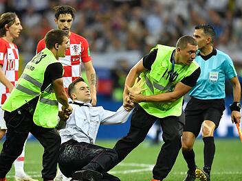 Pjotr Wersilow wird im WM-Finale von Ordnern abgeführt, nachdem er mit weiteren Aktivisten das Spielfeld gestürmt hatte. Foto: dpa-bildfunk