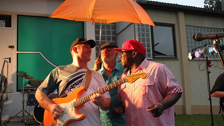 Gut beschirmt von Besucher Martin Knoch sangen und spielten Larry Rayford (rechts) und Stefan Kratofil von den "Orange Shakers" beim letztjährigen Sommerfest des Kleinkunstvereins "Tecnet Obermain". Für das diesjährige Sommerfest am 8. August wünschen sich die Musiker, dass sich diese Szene nicht wiederholen möge.  Foto: Stephan Stöckel