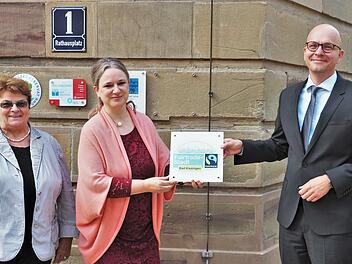 Oberbürgermeister Dirk Vogel (SPD) brachte gemeinsam mit Susanne Wahler-Göbel (Mitte), Vorsitzende der lokalen Steuerungsgruppe, und Stadträtin Martha Müller (DBK), offizielle Vertreterin der Stadt in der Gruppe, die Plakette "Fairtrade-Stadt" am Rathaustor an.
