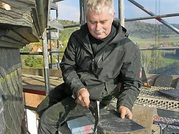 Ein Arbeitsplatz in luftiger Höhe: Bernd Voigt von der Firma Eber Bedachungen bringt eine Schieferplatte für die Turmfassade der St. Bartholomäus-Kirche in die richtige Größe. Fotos: Tobias Braunersreuther