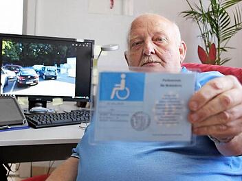 Klaus Bilstein zeigt seinen hellblauen Behinderten-Ausweis. Damit darf er als außergewöhnlich Gehbehinderter auf einem Behinderten-Parkplatz parken. Im Hintergrund auf dem Bildschirm das Foto des Behinderten-Parkplatzes am Schützenhaus Kronach. Der rechte und freie Platz wurde ihm verwehrt.  Foto: Friedwald Schedel